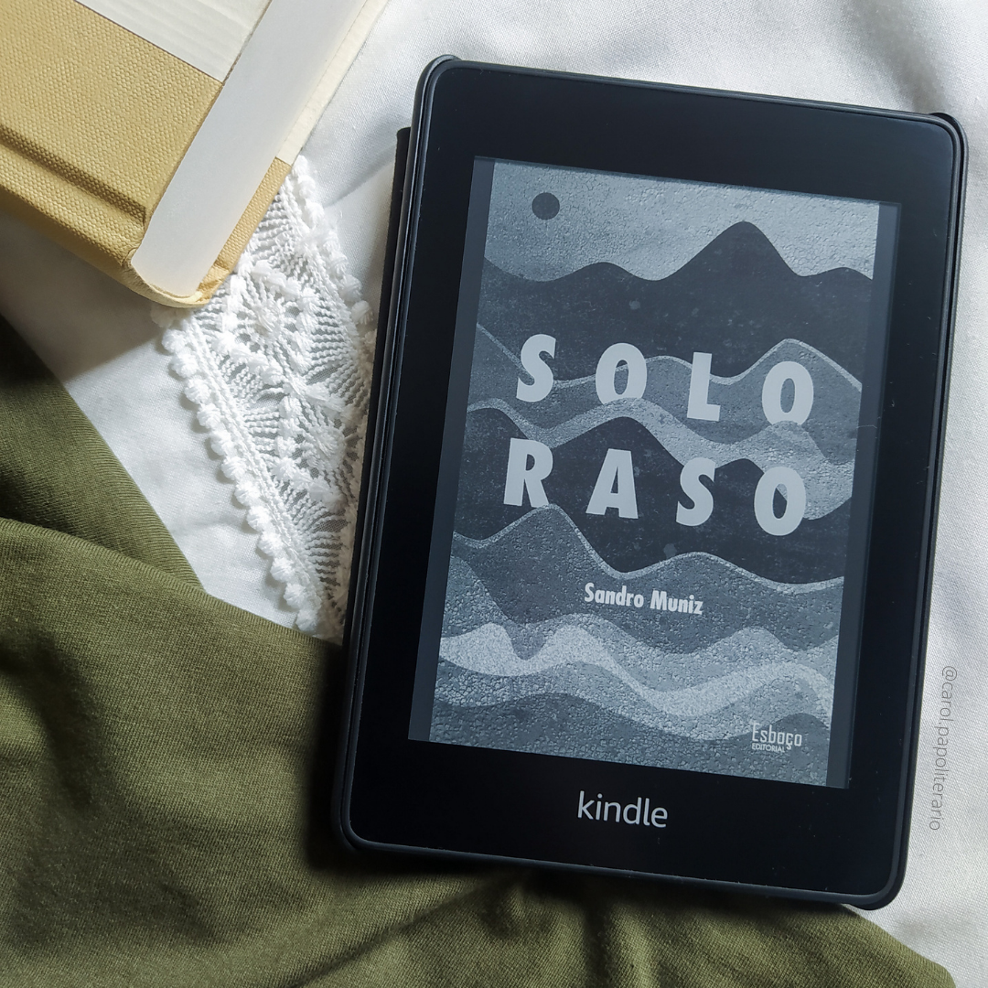 Kindle com a capa do livro Solo Raso, com um tecido no canto inferior esquerdo da imagem e um livro com capa lisa no canto superior esquerdo da imagem.